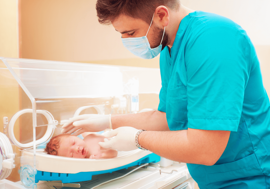 A female student is smiling as she looks down to her laptop, as she has her hands hovering slightly over its keyboard.