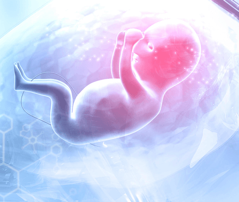 A female student is smiling as she looks down to her laptop, as she has her hands hovering slightly over its keyboard.